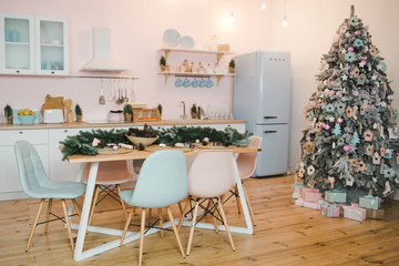 Interior light kitchen with christmas decor and tree. Christmas table setting.