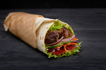 Tasty doner kebabs with fresh salad trimmings and shaved roasted meat served in tortilla wraps on brown paper as a takeaway snack - obrazy, fototapety, plakaty