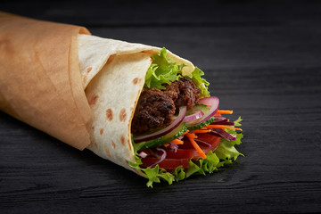 Tasty doner kebabs with fresh salad trimmings and shaved roasted meat served in tortilla wraps on brown paper as a takeaway snack