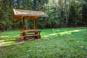 Wooden table with benches in glade in forest, place for picnic. - 303695595