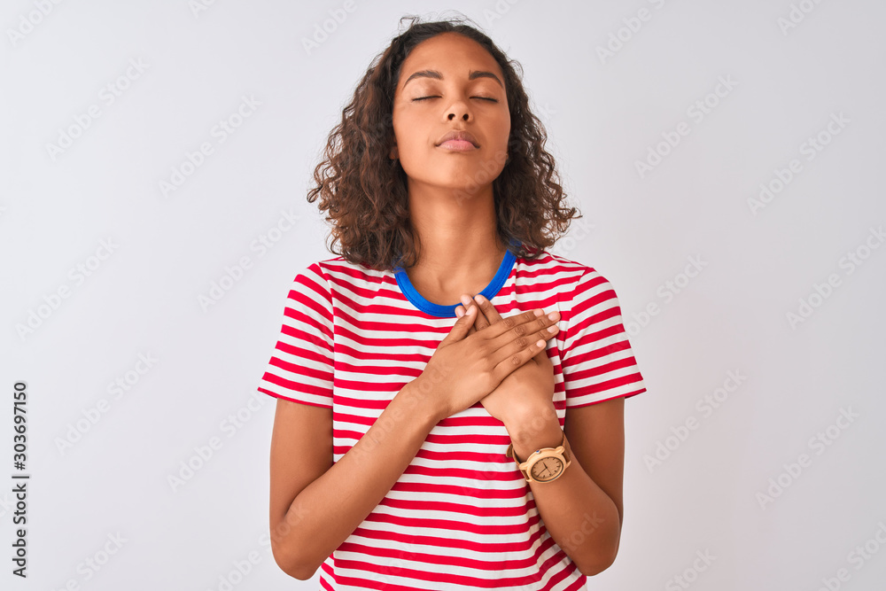 Canvas Prints Young brazilian woman wearing red striped t-shirt standing over isolated white background smiling with hands on chest with closed eyes and grateful gesture on face. Health concept.