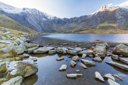 Early morning light and shadow over mountains and snow. Y Garn from Cwm Idwal. Lake or Llyn Idwal in foreground. Landscape, wide angle