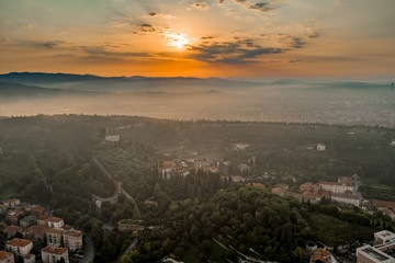 Fototapeta premium Aerial drone shot view of sunrise on foggy Veronetta colline with Castel San Pietro and funicolare