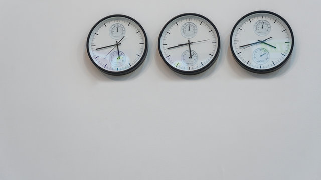 Three wall clocks showing time in different capitals of the world.
