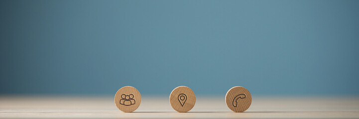 Wide view image of three wooden cut circles with contact and information icons on them