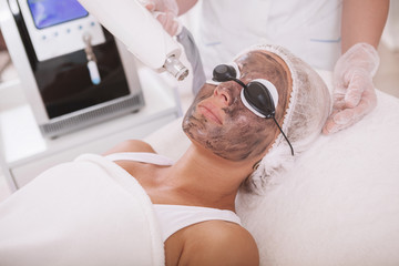 Cropped shot of a professional dermatologist doing carbon laser peel treatment on a female client