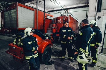 Full length portrait of confident firefighters by truck at fire station