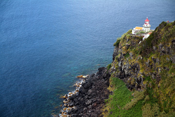 The white and red lighthouse on the green cliff