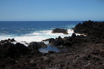 Fototapeta na wymiar The intense blue sea and the black volcanic rocks