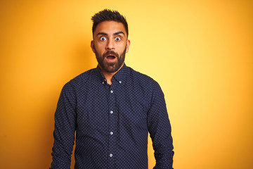 Young handsome indian businessman wearing shirt over isolated yellow background afraid and shocked with surprise expression, fear and excited face.