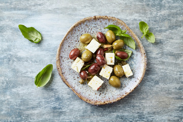 Green and kalamata olives, capers and feta cheese on rustic wooden background. Healthy Snack Idea. Top view.