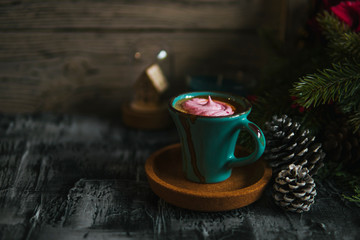 Obraz na płótnie Canvas Coffee cup, pink marshmallow, fir branch, pine cones, glass ball on dark rustic backdrop. For Christmas, new year winter holiday drink, beverage. Festive template, copy space, shallow depth of field