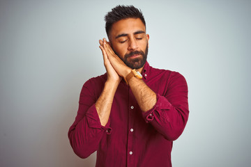 Young indian man wearing red elegant shirt standing over isolated grey background sleeping tired dreaming and posing with hands together while smiling with closed eyes.