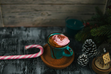 Coffee, pink marshmallow, fir branch, pine cone, candy cane on dark rustic backdrop. For Christmas, new year winter holiday drink, beverage. Festive template, copy space, shallow depth of field