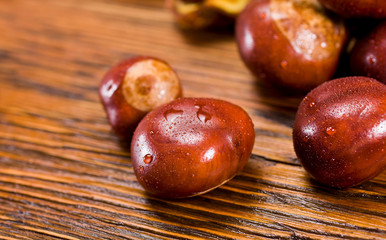 Chestnut fruits on a wet wooden table. Autumn background.