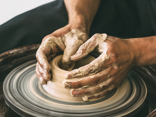 Ceramist at a pottery workshop A man is working behind a potter's wheel Close-up photo - obrazy, fototapety, plakaty