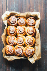 Cinnamon rolls with sugar icing  ready to be eaten for christmas holiday, top view over a rustic wooden  background