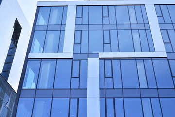Obraz na płótnie Canvas Modern office building wall made of steel and glass with blue sky