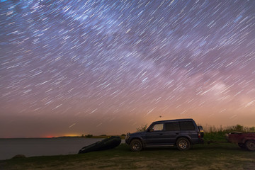 Fototapeta na wymiar SUV under the starry sky on the shore of the bay
