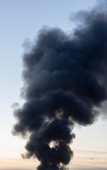 Black toxic smoke from burning garbage rises into the sky and pollutes the environment. Fire in a landfill at night.