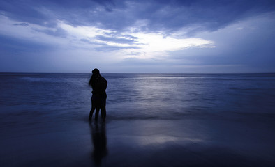 Fototapeta premium couple standing in the sea at sunset blue tones