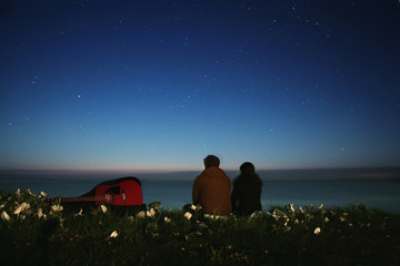 couple with a guitar on the beach under the stars