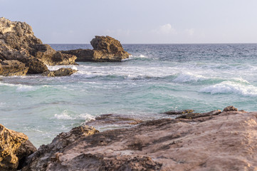 Fototapeta na wymiar Caribbean sea coast with rocks and hello breaking