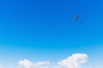 Paraglider flying over the mountains on a bright summer day. Paragliding sport concept. Copy space.
