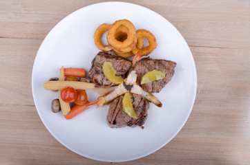 Grilled meat accompanied by onion rings and salad