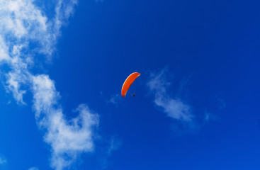 Paraglider flying over the mountains on a bright summer day. Paragliding sport concept. Copy space.