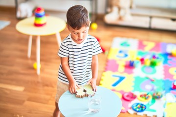 Beautiful toddler boy standing at kindergarten with lots of toys