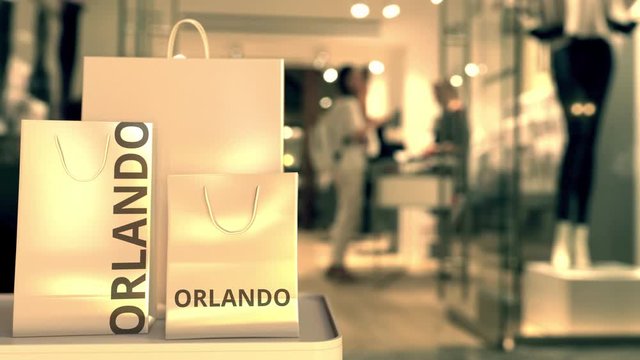 Paper shopping bags with Orlando caption against blurred store entrance. Retail in the United States related 3D animation