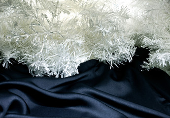 New year decoration. White fir branches with transparent snowflake on the black textile background.