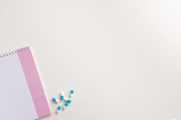 Pills and notebook on white background. Medical concept. Flat lay.