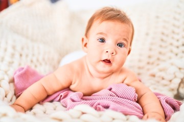 Adorable baby lying down over blanket on the sofa at home. Newborn relaxing and resting comfortable