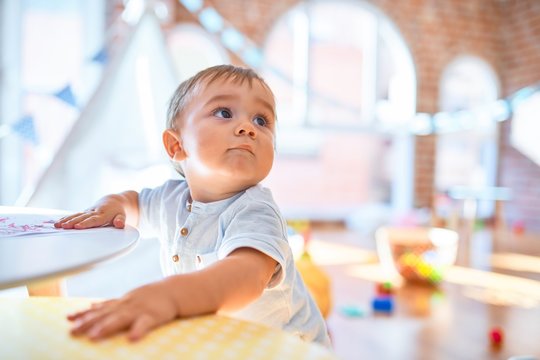 Adorable toddler standing around lots of toys at kindergarten