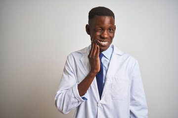 Young african american doctor man wearing coat standing over isolated white background touching mouth with hand with painful expression because of toothache or dental illness on teeth. Dentist concept