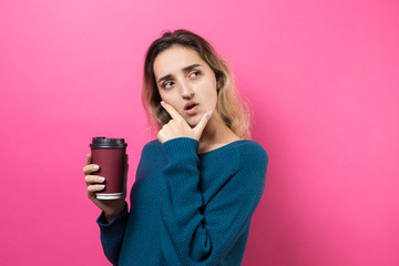 Glamor woman in glasses in an orange sweater with a drink of coffee on a pink background..	