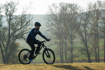 Fototapeta na wymiar Cyclist in pants and fleece jacket on a modern carbon hardtail bike with an air suspension fork rides off-road. 
