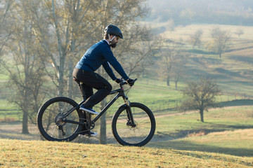 Fototapeta na wymiar Cyclist in pants and fleece jacket on a modern carbon hardtail bike with an air suspension fork rides off-road. 