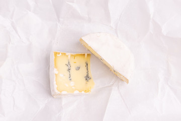 Blue cheese with white surface, isolated on white background, soft light, studio photo. Mix of gorgonzola and camembert / brie cheese.