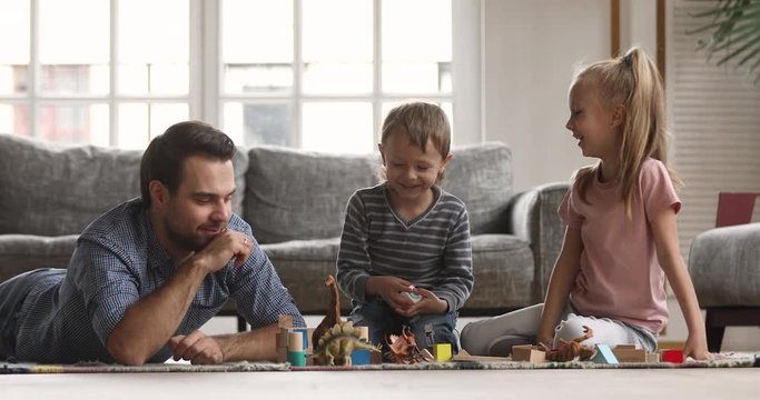 Loving young dad and small children playing together at home