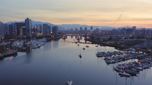 Aerial: Yachts moored in False Creek and the Vancouver city skyline at sunrise, British Columbia, Canada
