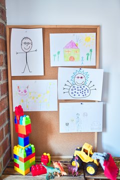 Art corner with cute draws strug up on cork board and toys at kindergarten