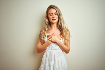 Young beautiful woman wearing casual dress standing over white isolated background smiling with hands on chest with closed eyes and grateful gesture on face. Health concept.
