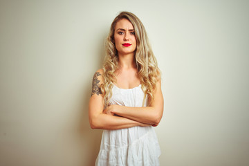 Young beautiful woman wearing casual dress standing over white isolated background skeptic and nervous, disapproving expression on face with crossed arms. Negative person.