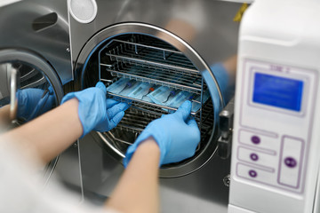 Dentist is loading dental probes into sterilize machine - obrazy, fototapety, plakaty
