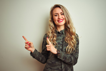 Young beautiful woman wearing military camouflage shirt over white isolated background smiling and looking at the camera pointing with two hands and fingers to the side.