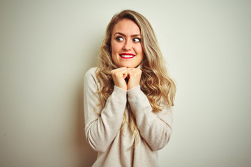 Beautiful woman wearing winter turtleneck sweater over isolated white background laughing nervous and excited with hands on chin looking to the side