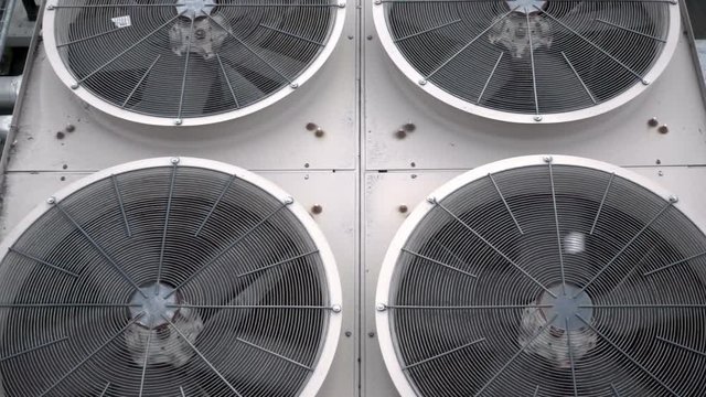 Tilting shot of some very large condenser fans on top of an industrial chiller unit
